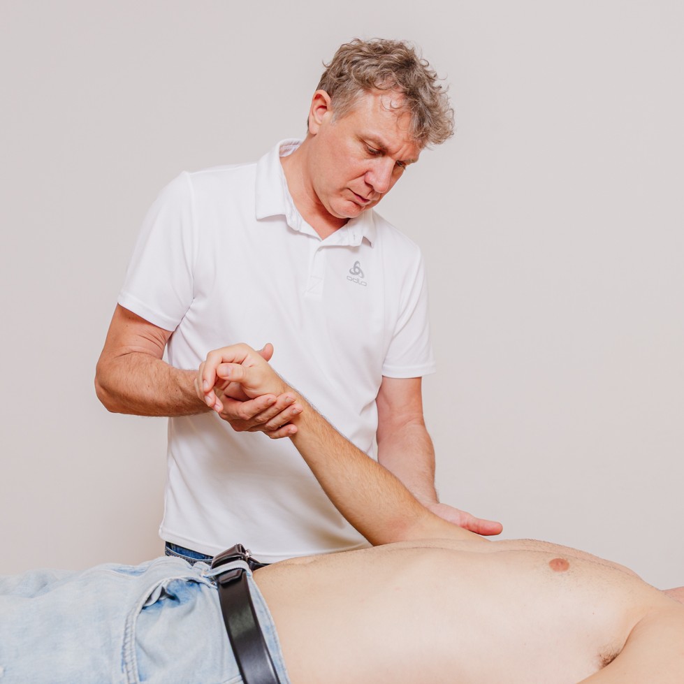 Andreas sitzt auf einem Baumstamm über dem Wasser